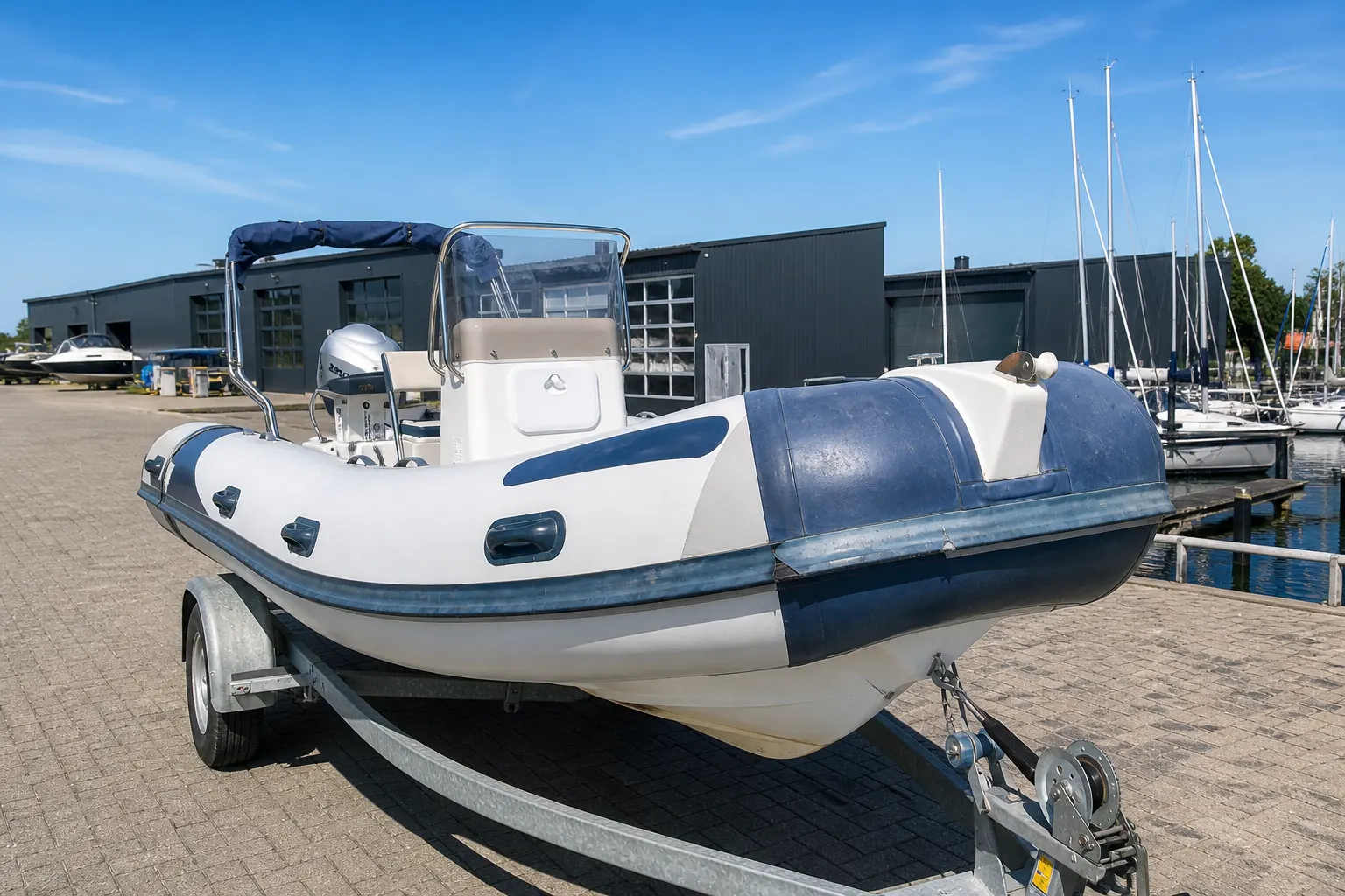 Een RIB op een trailer. Links zijn de tubes en de wrijfrand weer heel en diep van kleur, rechts zijn ze verbleekt, vuil en beschadigd.